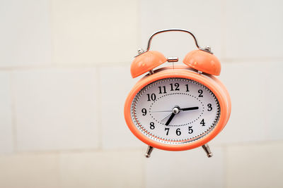 Retro style orange alarm clock flying in the bathroom.