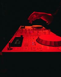 Close-up of hand on red light painting against black background