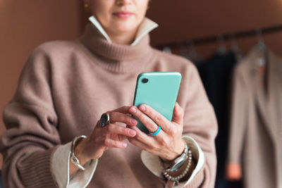 Cropped picture fashion woman standing in modern work place or office with smartphone