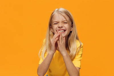 Portrait of girl with hands clasped against orange background