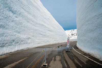 Road amidst snow covered mountain against sky