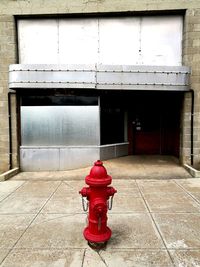 Red fire hydrant on footpath against building