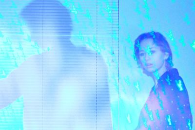 Woman standing by swimming pool against wall