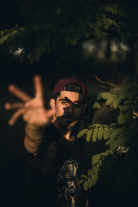 High angle view of young man with hand raised standing by trees