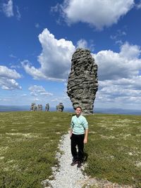 Full length of man on rock on field against sky