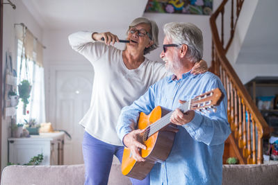 Senior man playing guitar with wife at home