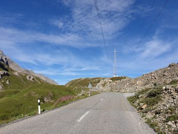 Country road by mountain against sky