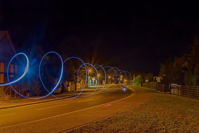 Light trails on road against sky at night