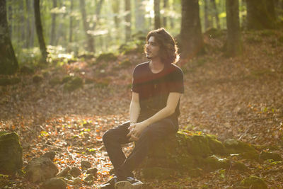 Young man sitting in forest