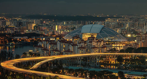 Illuminated bridge over river against buildings in city at night