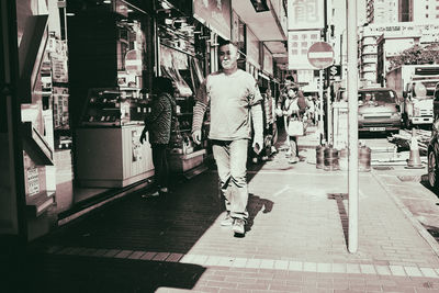 Rear view of people walking on street in city