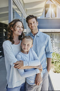 Happy family standing on terrace, embracing daughter