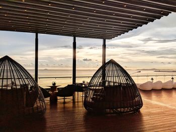 Deck chairs at beach against sky during sunset