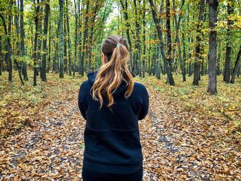 Midsection of woman standing by tree in forest during autumn