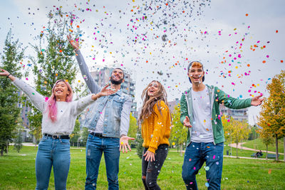 Smiling friends standing amidst confetti in park