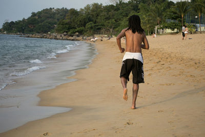 Rear view of two women walking on beach