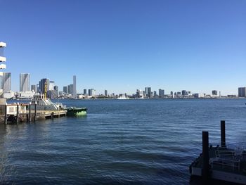 City at waterfront against blue sky