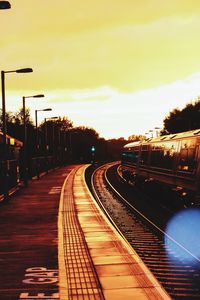 Train on railroad tracks against sky at sunset