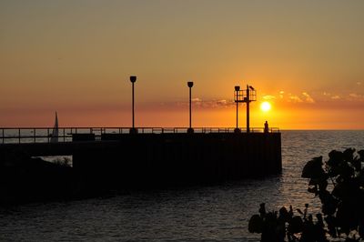 Silhouette people on sea against sky during sunset