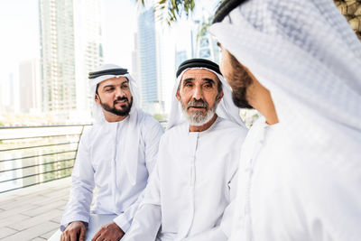 Senior man with grandsons wearing dish dash sitting outdoors