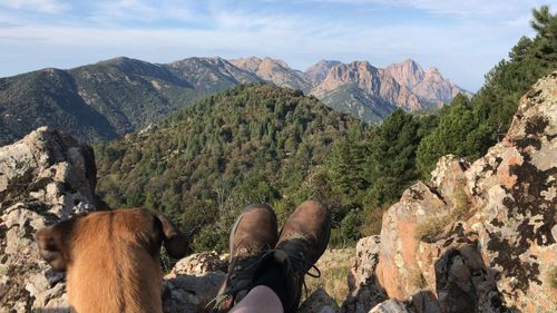 Low section of person on rocks against mountains