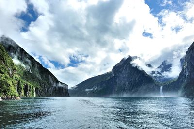 Scenic view of lake and mountains against cloudy sky