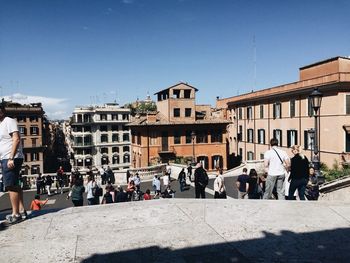 People in city by buildings against sky