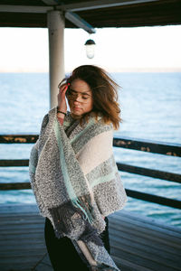 Young woman standing on pier against sea