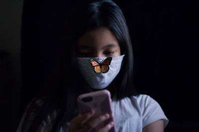 Girl using smart phone against black background