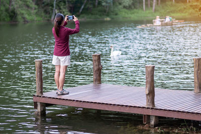 Full length of woman standing on pier over lake