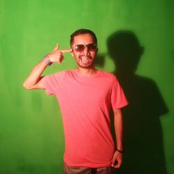 Portrait of man wearing sunglasses standing against gray background