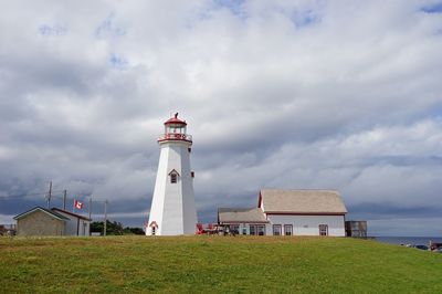 Lighthouse by buildings against sky