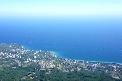 High angle view of townscape by sea against blue sky