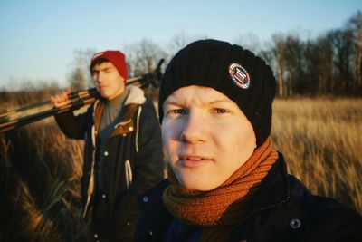 Portrait of friends standing on field against blue sky during sunset