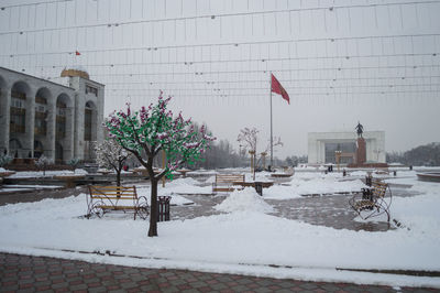 Snow covered buildings by city during winter