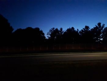 Silhouette trees on field against clear sky at night