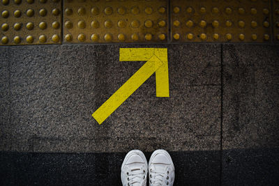 Low section of person standing on road sign