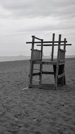 Lifeguard chair on beach against sky