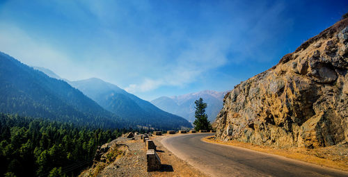 Road by mountains against sky