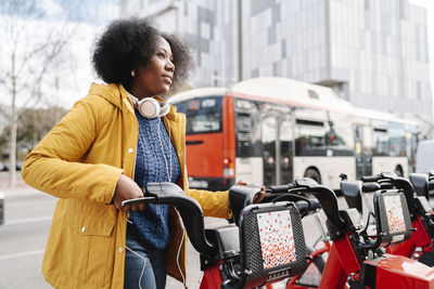 Thoughtful woman standing at bicycle parking station