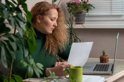 Young woman using mobile phone while sitting on table