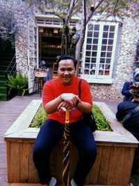 Full length of man sitting in yard against building