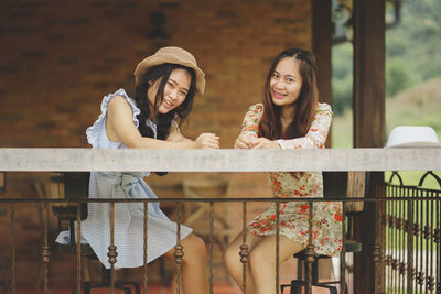 Portrait of smiling young woman standing against railing