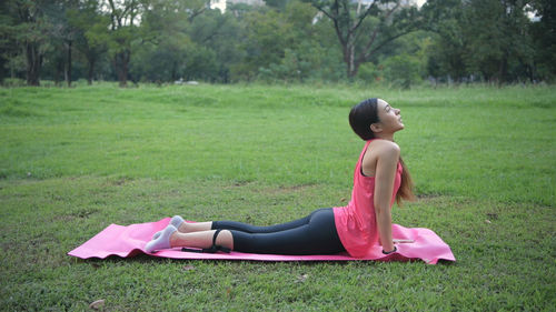 Side view of woman sitting on grassy field