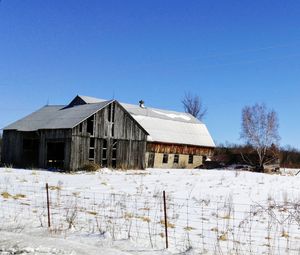 House on field against clear sky during winter