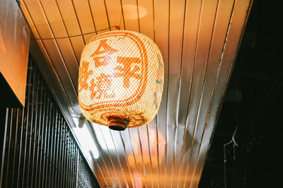 Low angle view of illuminated lighting equipment hanging on ceiling