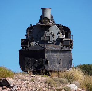 Abandoned train on field against clear sky