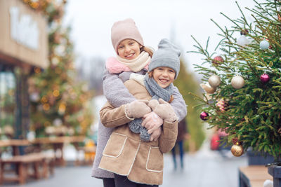 Portrait of woman standing against christmas tree