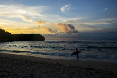 Silhouette person on beach against sky during sunset