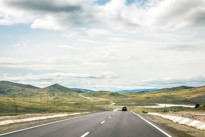 Road by mountains against sky